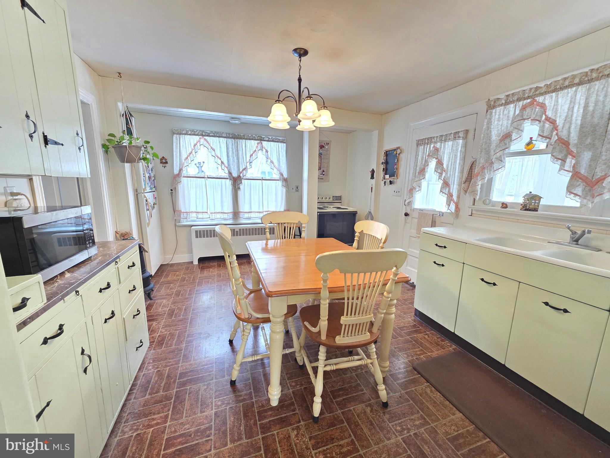 3016 County House Road Woodbury, NJ 08096 - Photo 8 of 19 a dining room with wooden floor a chandelier a wooden table and chairs