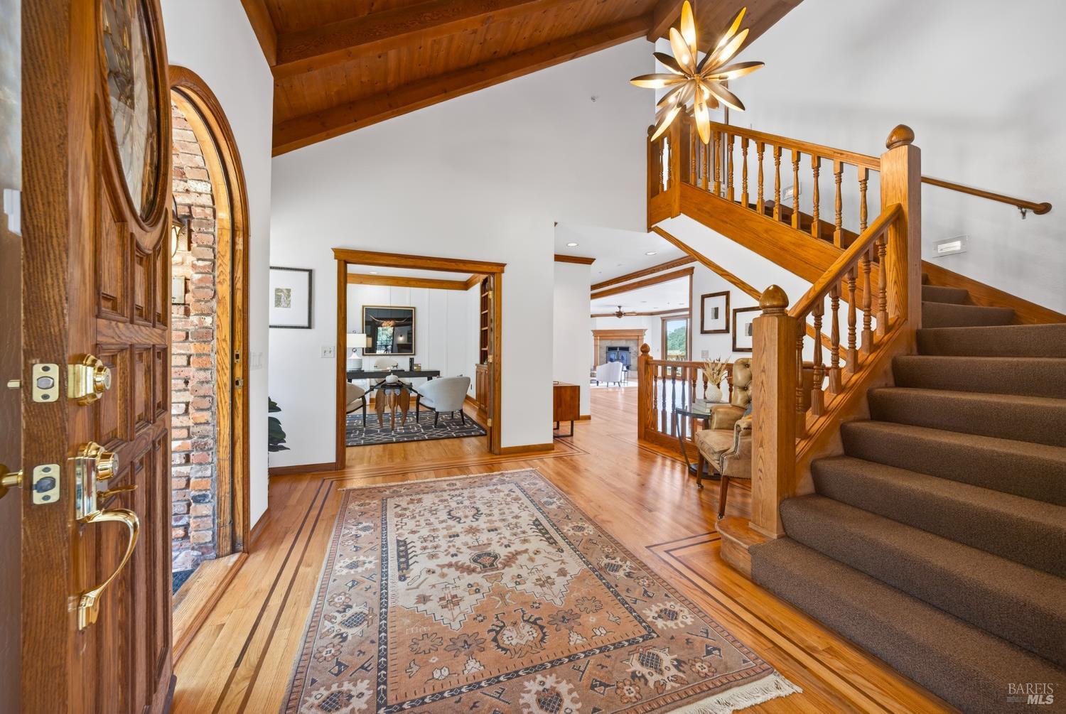 10 Lockton Lane Novato, CA 94945 - Photo 4 of 68 A grand foyer introduces the home with a dramatic staircase, warm wood detailing, and sightlines through the house toward the deck and rolling landscape beyond.