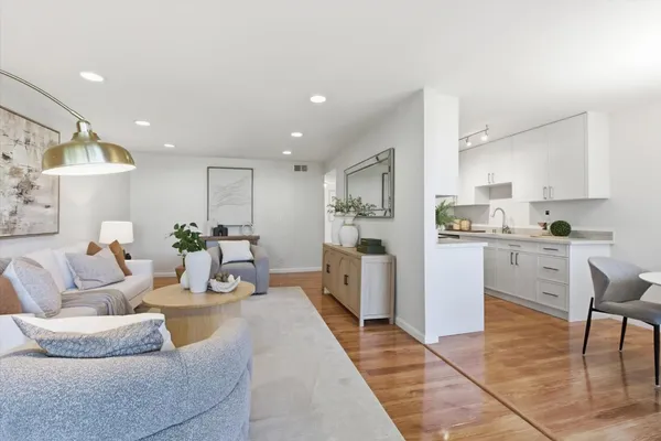 a living room with furniture a wooden floor and kitchen view