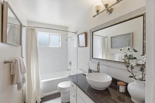 a bathroom with a granite countertop sink toilet a mirror and shower