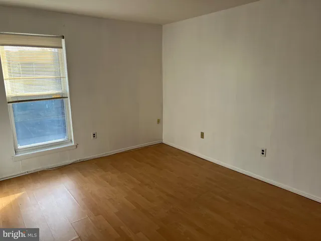 a view of an empty room with wooden floor and closet