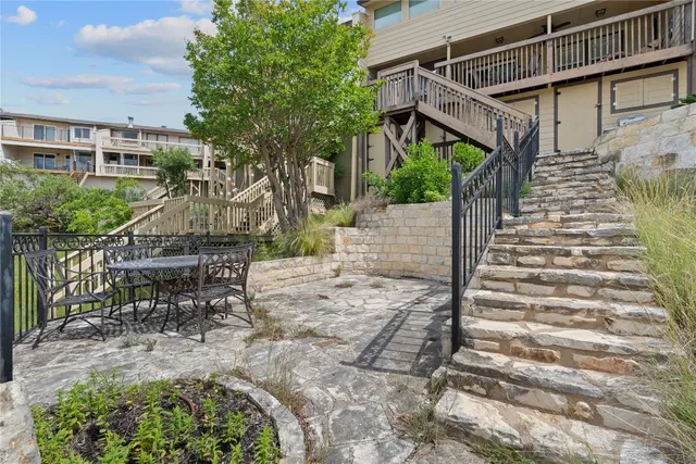 a view of house with wooden stairs and a bench in a patio