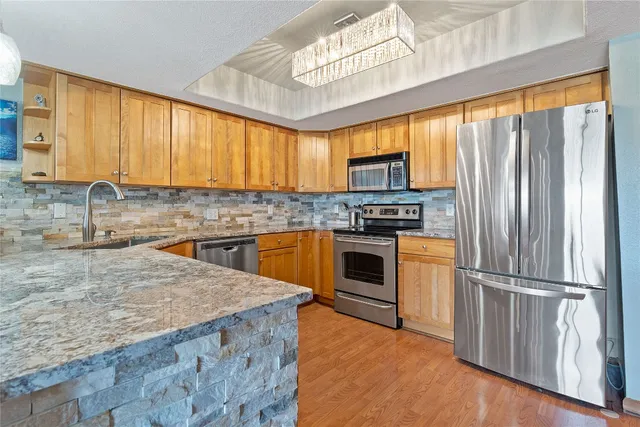 a kitchen with a sink a kitchen island a stove a refrigerator cabinets and a window