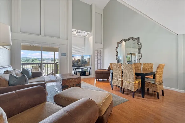 a living room with furniture a large window and wooden floor