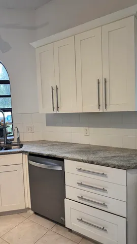 a kitchen with granite countertop white cabinets and a sink