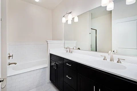 a bathroom with a double vanity sink a mirror and a bathtub