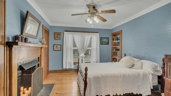 a bedroom with a bed dresser and a fireplace