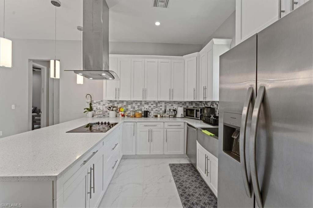 3219 64th Avenue Northeast Naples, FL 34120 - Photo 1 of 33 Kitchen with tasteful backsplash, appliances with stainless steel finishes, a peninsula, island range hood, and marble finish floor