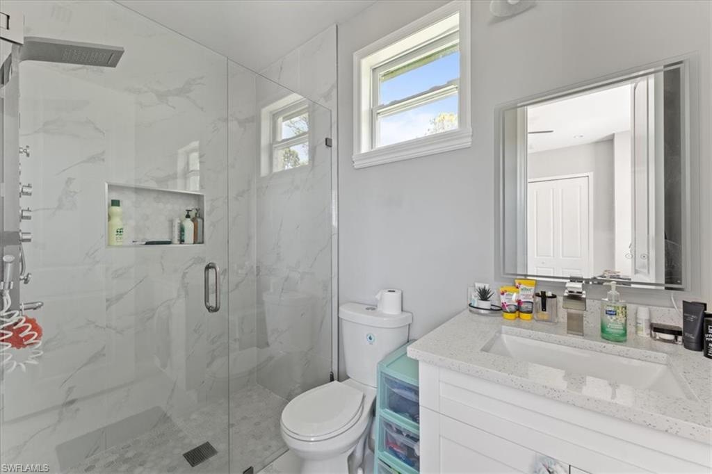 3219 64th Avenue Northeast Naples, FL 34120 - Photo 16 of 33 Full bath with a marble finish shower, toilet, and vanity