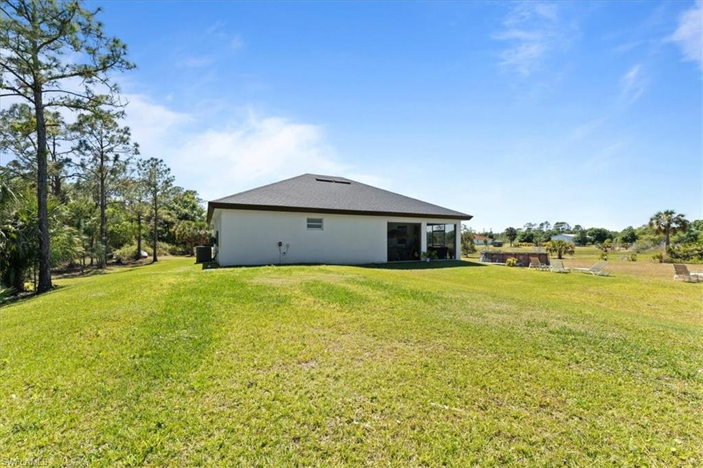 3219 64th Avenue Northeast Naples, FL 34120 - Photo 25 of 33 Back of property featuring a lawn and stucco siding