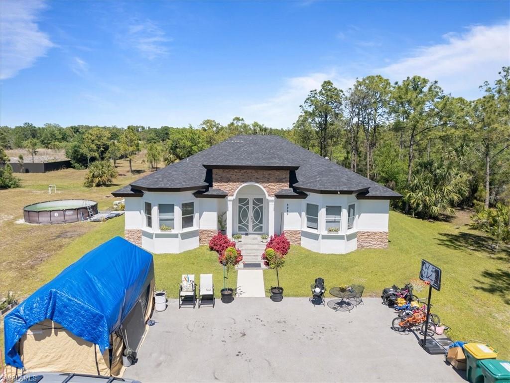 3219 64th Avenue Northeast Naples, FL 34120 - Photo 27 of 33 Back of property with stucco siding, a lawn, and roof with shingles