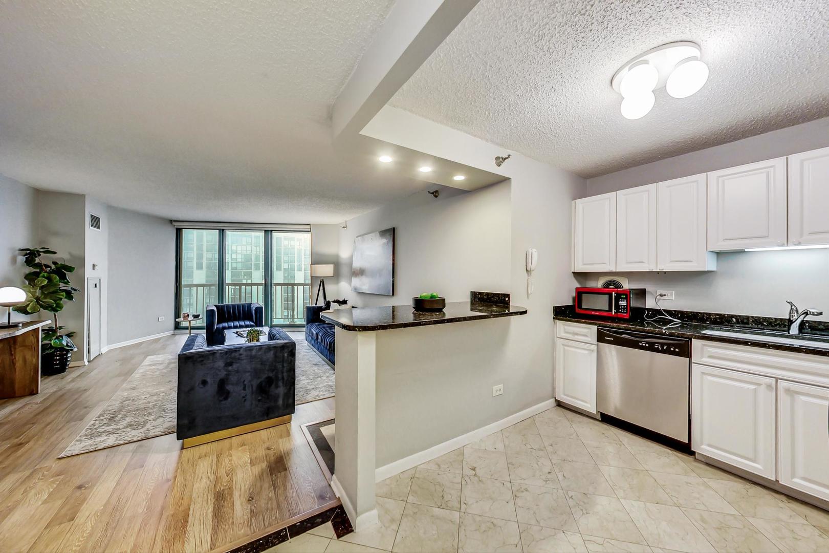 111 West Maple Street, Unit 3005 Chicago, IL 60610 - Photo 4 of 18 a kitchen with stainless steel appliances granite countertop a stove top oven a sink a dining table and chairs with white cabinets