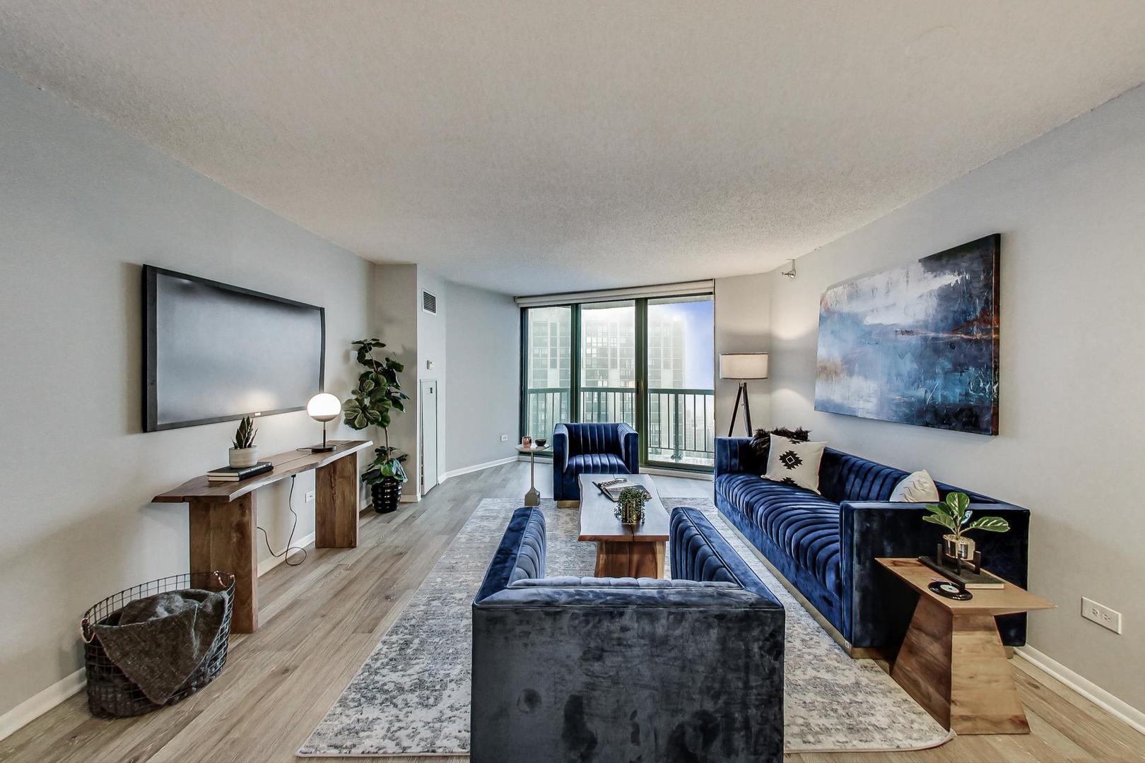 111 West Maple Street, Unit 3005 Chicago, IL 60610 - Photo 6 of 18 a living room with furniture a flat screen tv and a floor to ceiling window