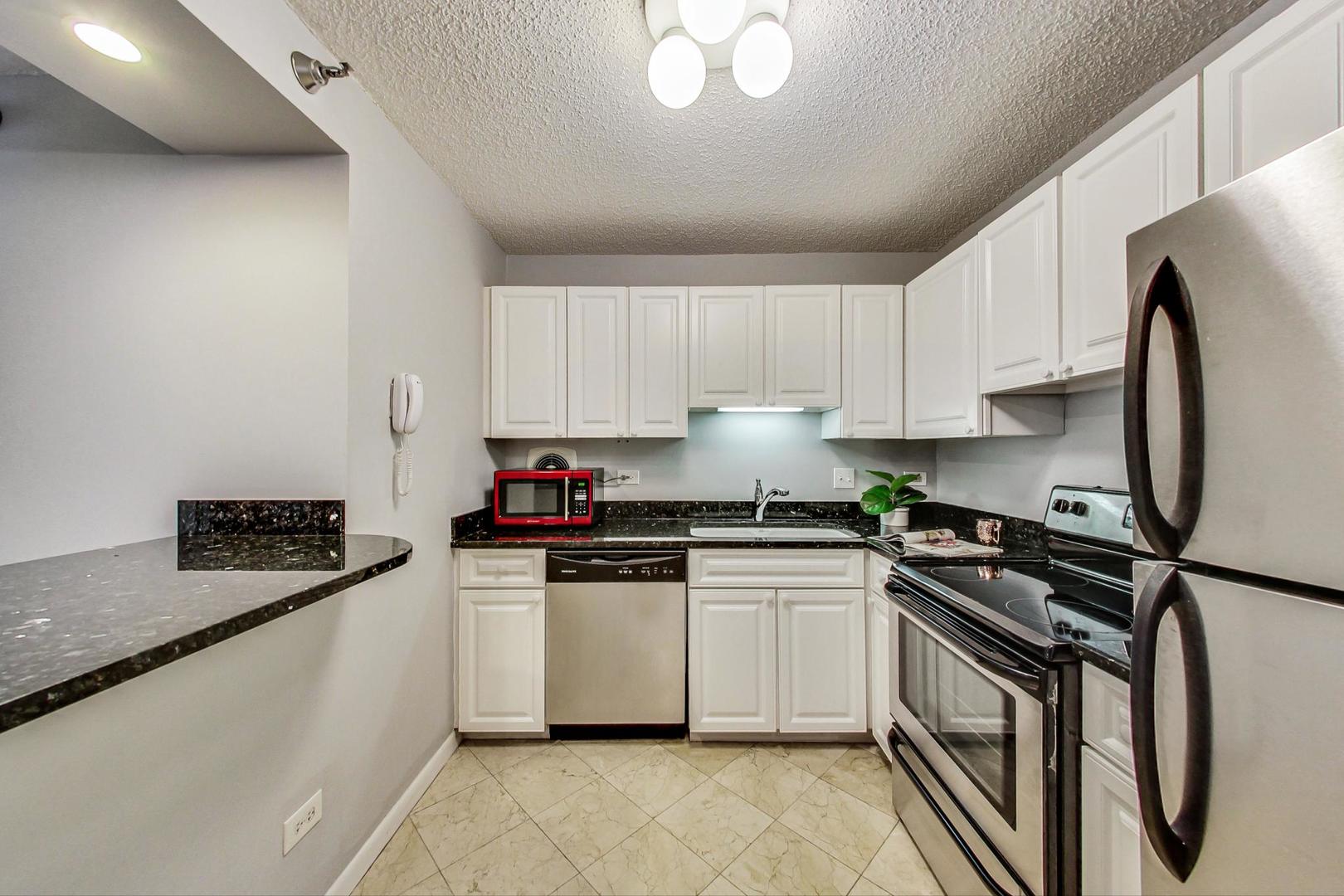111 West Maple Street, Unit 3005 Chicago, IL 60610 - Photo 9 of 18 a kitchen with stainless steel appliances granite countertop a stove a sink and a refrigerator