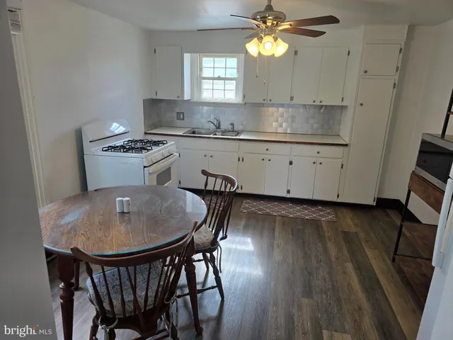a kitchen with kitchen island granite countertop a sink a stove a dining table and chairs