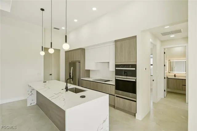 a large kitchen with kitchen island a counter space a sink a center island stainless steel appliances and a refrigerator