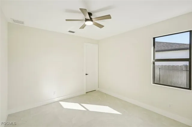 an empty room with a window and a ceiling fan