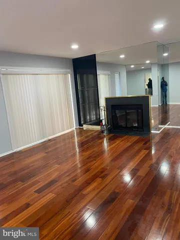 an empty room with wooden floor fire place and windows