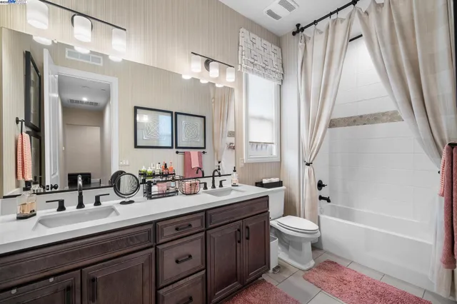 a bathroom with a double vanity sink toilet mirror and bathtub