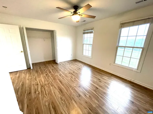 a view of an empty room with a window and wooden floor