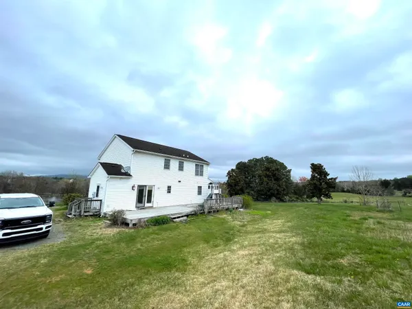a view of a white house with a big yard and large trees