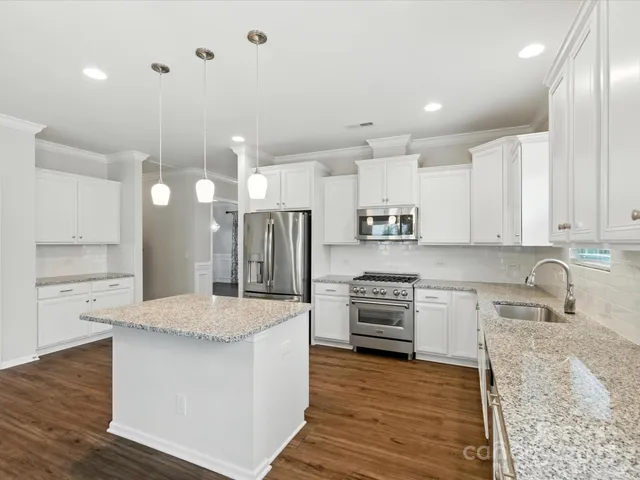 a large kitchen with granite countertop a stove top oven a sink a counter space and cabinets