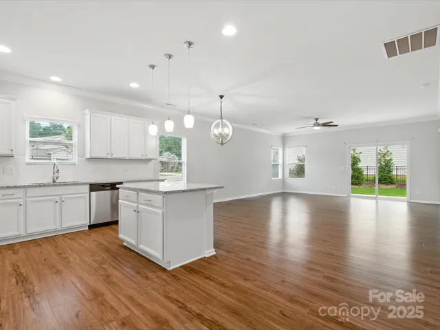 a large kitchen with hardwood floor a sink stainless steel appliances and cabinets