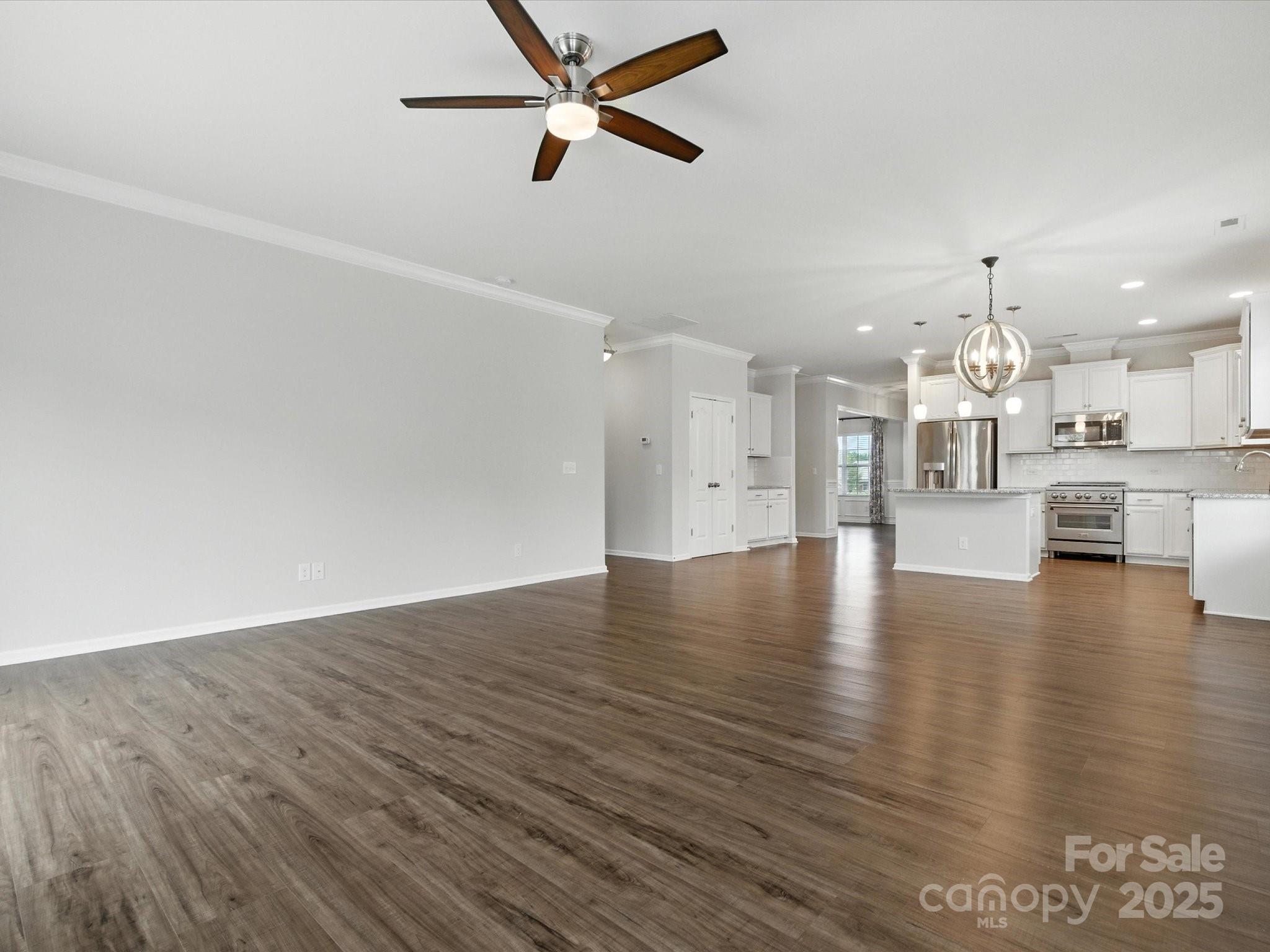 1628 Spring Blossom Trail Fort Mill, SC 29708 - Photo 17 of 42 an empty room with wooden floor kitchen view and a chandelier