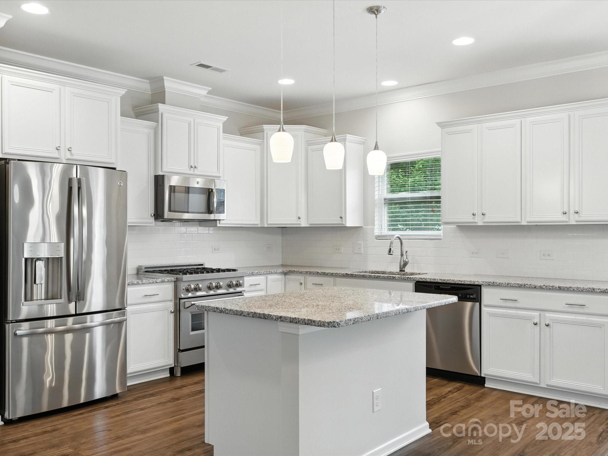 1628 Spring Blossom Trail Fort Mill, SC 29708 - Photo 9 of 42 a kitchen with stainless steel appliances granite countertop a sink stove a refrigerator and white cabinets with wooden floor