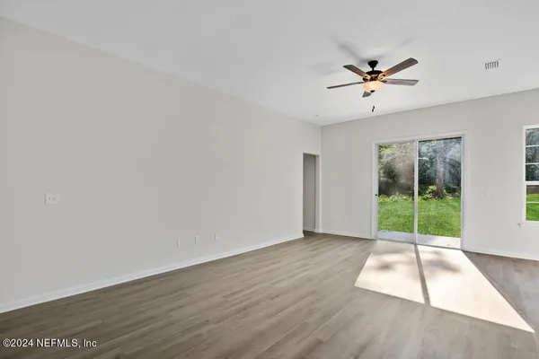 a living room with furniture kitchen view and a wooden floor