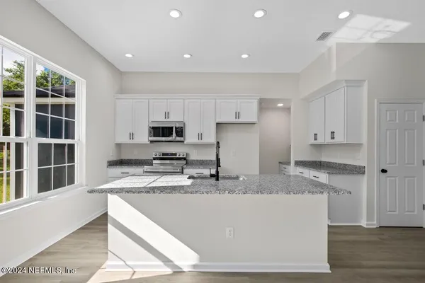 a kitchen with granite countertop a sink a stove and cabinets