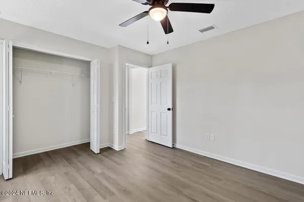 a view of empty room with wooden floor and fan