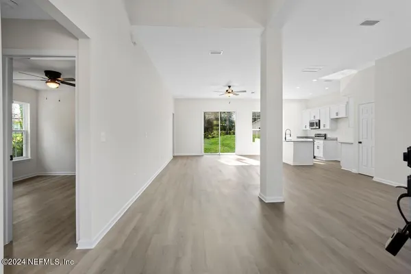 an empty room with wooden floor cabinet and windows