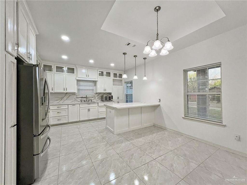 7723 Villa Rama S Street Mission, TX 78572 - Photo 6 of 15 a large white kitchen with granite countertop a refrigerator a oven a sink and a chandelier