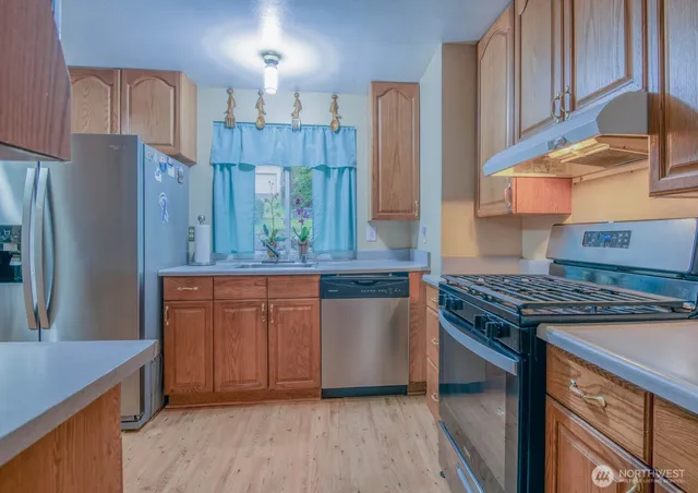a kitchen with stainless steel appliances granite countertop a stove a refrigerator and a wooden cabinets