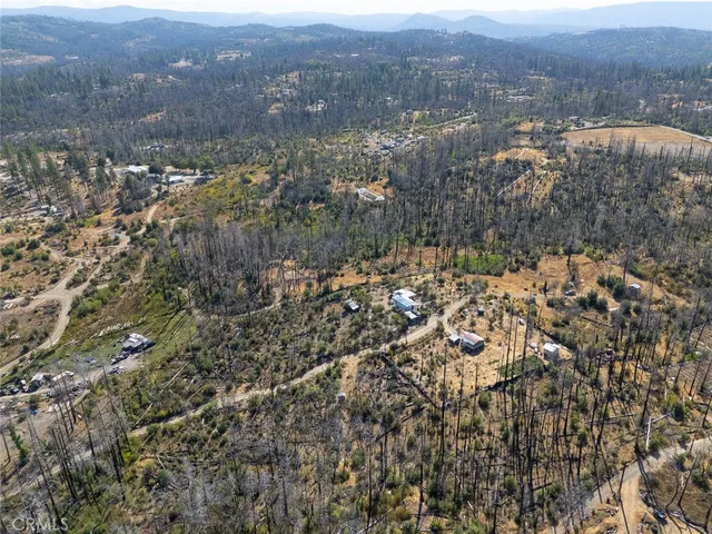 an aerial view of house with yard and mountain view in back