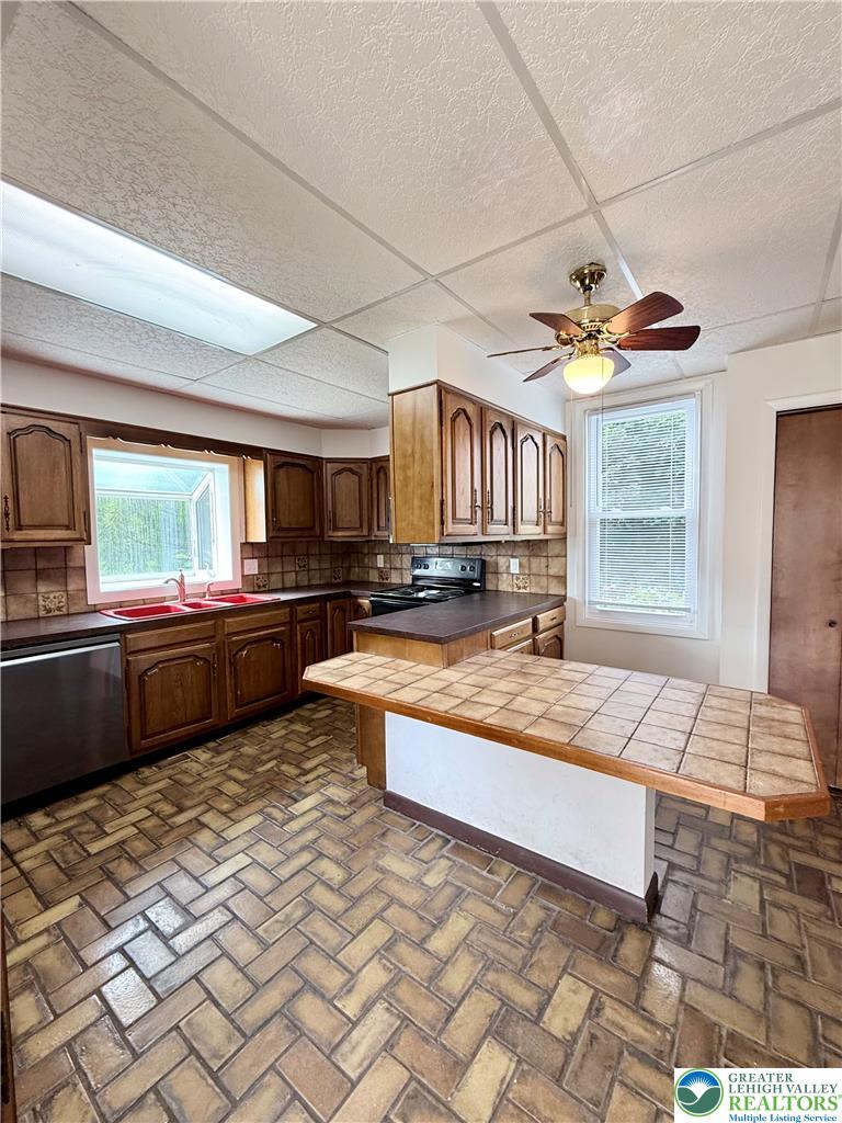 5540 Main Street Whitehall, PA 18052 - Photo 8 of 53 A functional kitchen features an island with tile counter, rich wood cabinetry, and patterned tile flooring.