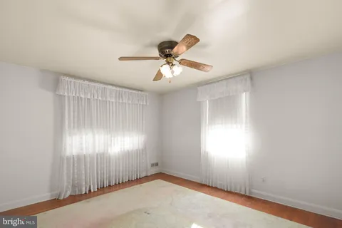 a view of a room with a ceiling fan and carpet