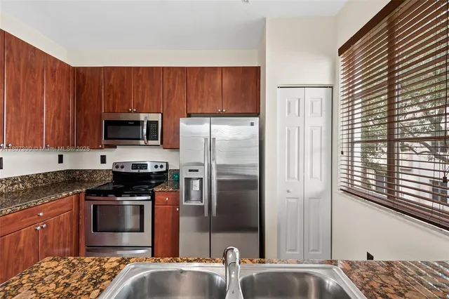 a kitchen with stainless steel appliances granite countertop a stove a sink and a microwave