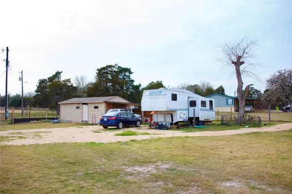 a view of a house with a big yard and large trees