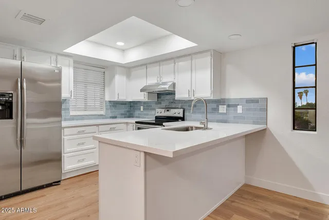 a kitchen with a sink a refrigerator a window and cabinets