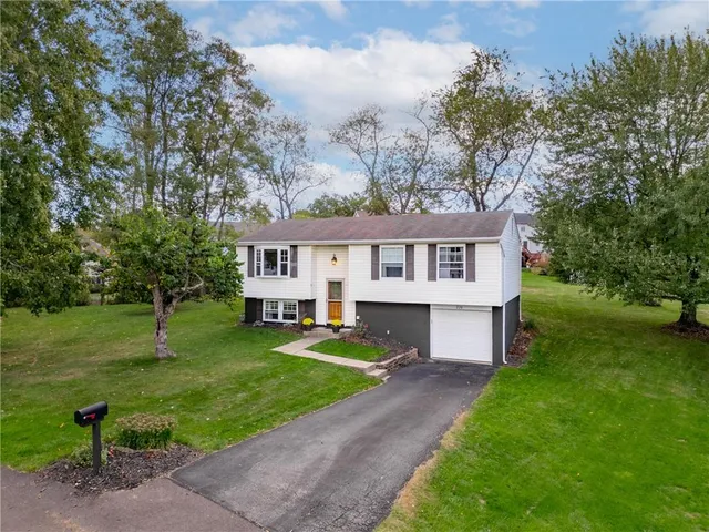 a front view of a house with a yard and trees