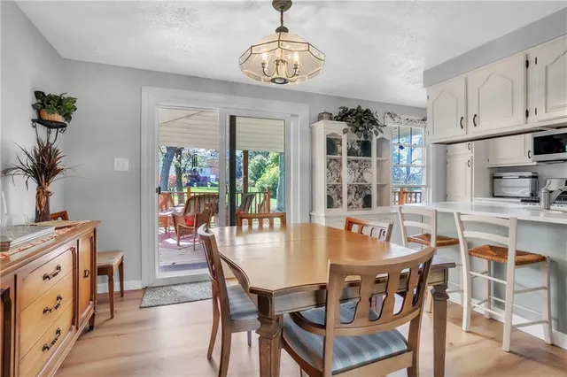 a dining room with wooden floor a chandelier a wooden table and chairs