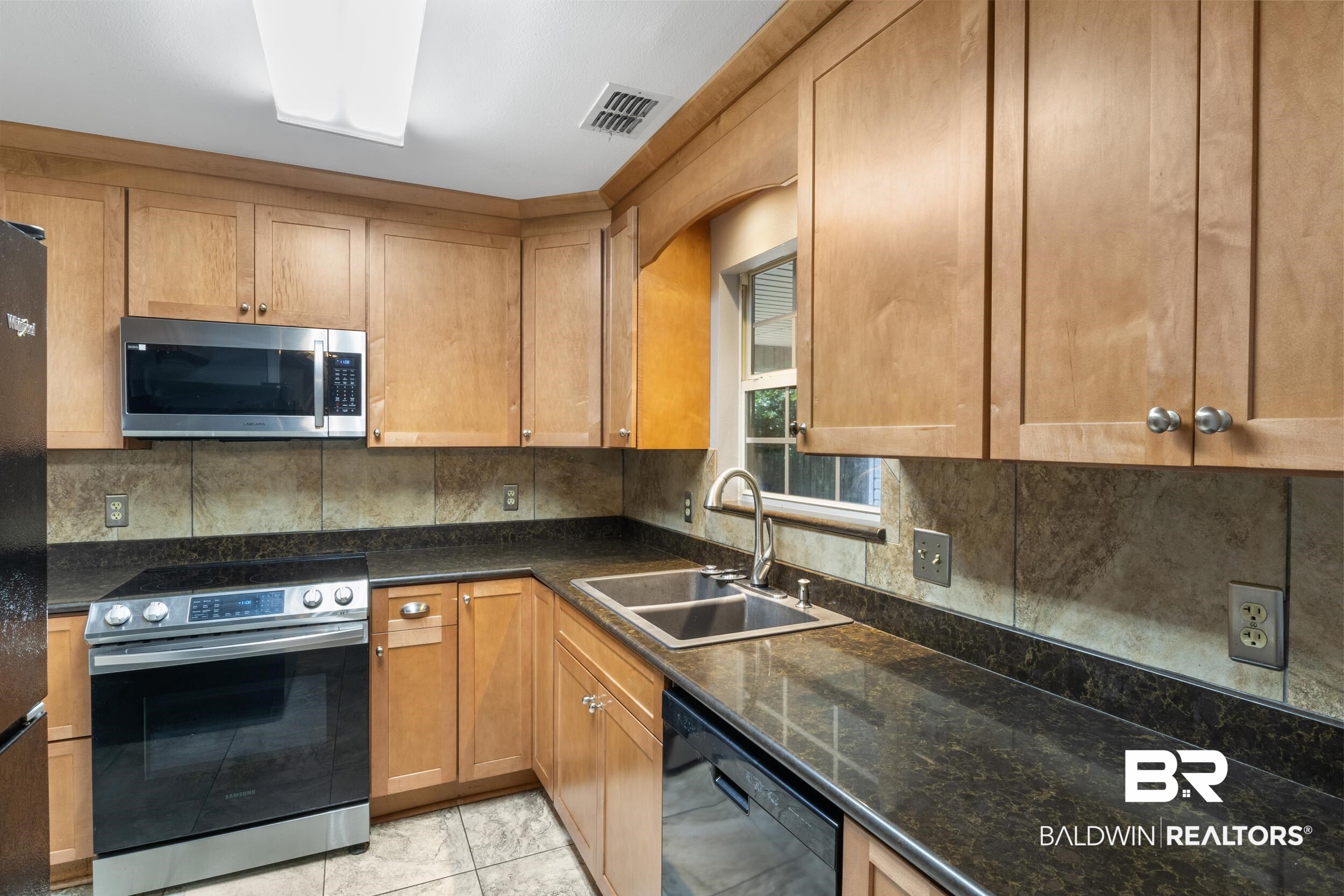 150 Montclair Loop Daphne, AL 36526 - Photo 18 of 29 Kitchen with dark stone counters, backsplash, appliances with stainless steel finishes, sink, and light tile floors