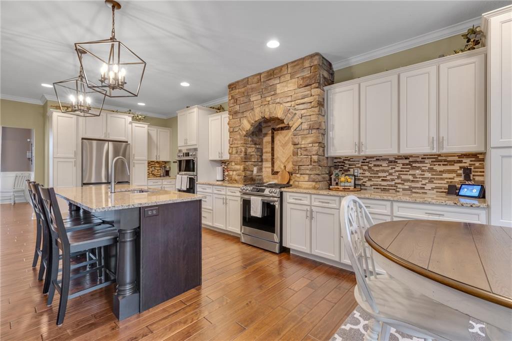 125 James Drive Beaver, PA 15009 - Photo 9 of 40 a kitchen with stainless steel appliances granite countertop a sink a stove a kitchen island with a dining table and wooden floor