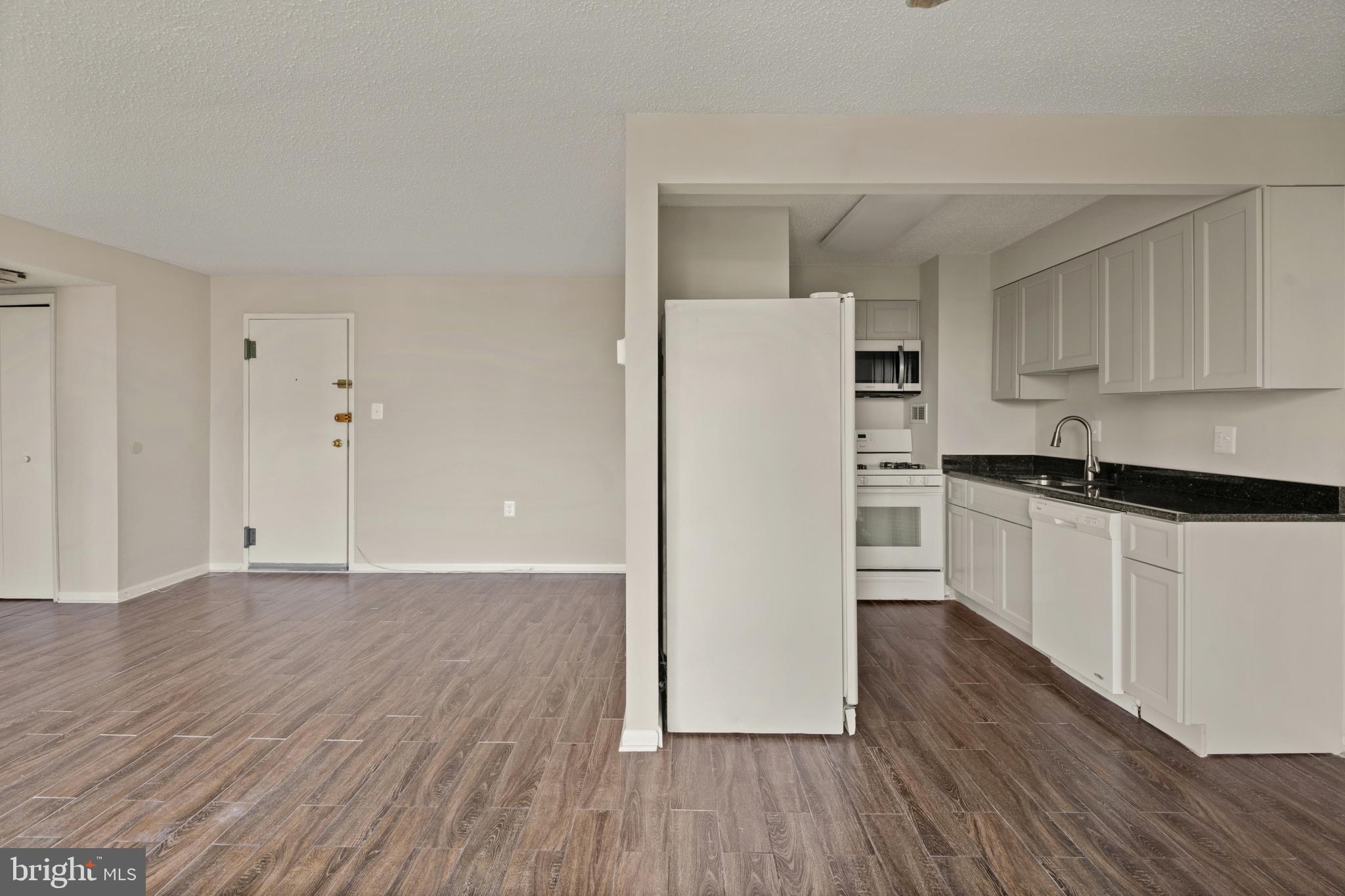 1824 Metzerott Road, Unit 303 Adelphi, MD 20783 - Photo 4 of 28 a kitchen with granite countertop a refrigerator and a stove top oven