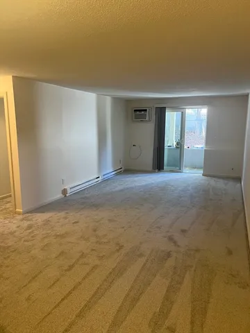 a view of an empty room with window and a kitchen