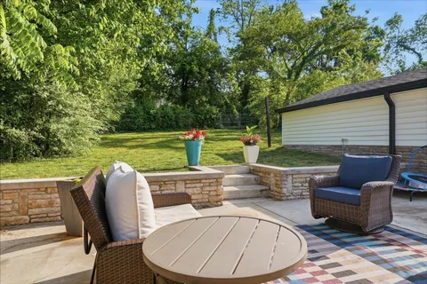 a view of a patio with table and chairs potted plants and large tree