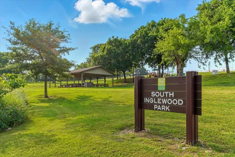 a view of a park that has a sign board large trees