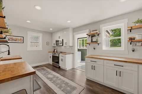 a kitchen with a stove a sink a oven a counter top space and windows